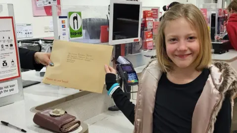 BBC Lily-Mae holding an envelope addressed to the Princess Trust