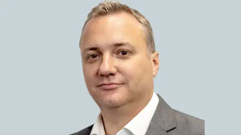 Avon Protection Image of Steve Elwell wearing a white shirt and grey suit jacket