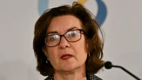 A head and shoulders shot of Eluned Morgan, who is speaking in front of a white backdrop.