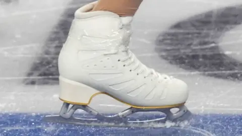 A white ice skate on a blue, white and black marked ice rink