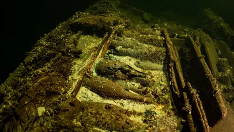 Tomasz Stachura / Baltictech A shipwreck on the bottom of the sea in which old champagne bottles can be seen in the middle