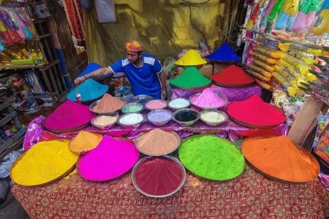 Getty Images A seller organizes various color powders called ''abir'' for sale at a market ahead of the Holi festival celebration in Kolkata, India, on February 25, 2026. 