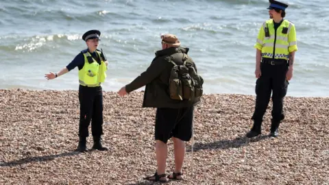 PA Media Police instruct walker on beach in Briton, East Sussex