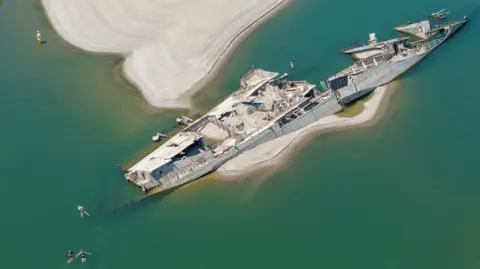 Reuters A drone view shows people swimming near a sunken German warship from World War II, exposed due to low Danube River levels caused by drought and extreme heat, in Prahovo, Serbia, July 30, 2026