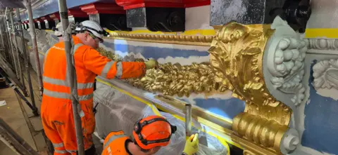 City of Edinburgh Council Workers in bright orange overalls repairing some of North Bridge's cast iron detail
