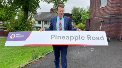 WMCA Andy Street with a Pineapple Road sign