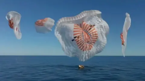 Four parachutes deployed as capsule floats on sea