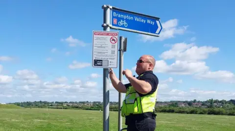 Northamptonshire Police Police officer installing signage to warn against motorcycle nuisance