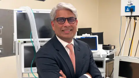 Professor Jim Khan in an operating theatre wearing a suit