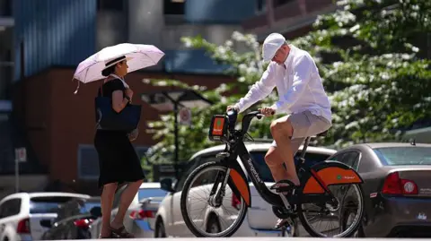  A woman walks with an umbrella to protect herself from the sun in Toronto, Ontario 