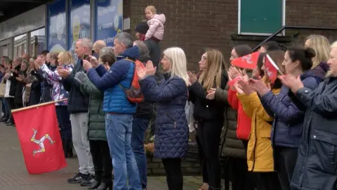 People lining the street in Onchan clapping