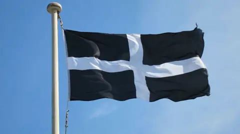The St Piran's flag - the flag of Cornwall - with a dark blue background and white cross, is seen blowing in the wind 
