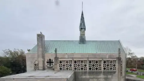A view of the Shrine church with a green roof surround by grass
