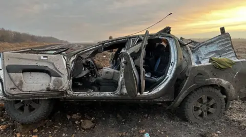 KVPU, the Independent Union of Ukrainian Miners A burnt out pick-up truck in a field full of mud and rubble. One of the doors is inside out and the inside of the vehicle is destroyed