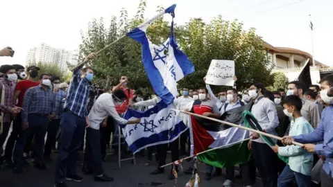 EPA Iranian students burn Israeli flags during a protest outside the UAE embassy in Tehran, Iran (15 August 2020)