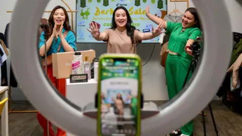 Getty Images Monica Amadea owner of a TikTok sales channel called Monomolly and her employees offering merchandise through a TikTok livestream in Jakarta.