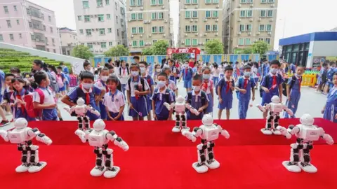 Getty Images Little Nao robots lined up in front of schoolchildren