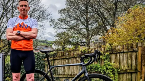 Muscular Dystrophy UK Scott Mitchell stood next to his bike after cycling the challenge