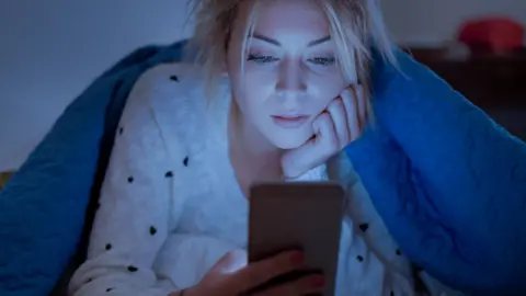 Getty Images A woman using her phone in bed