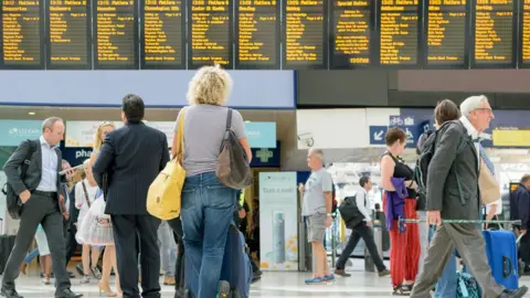 Alamy Commuters in a train station looking at the arrivals board