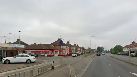 Google Street view image of a long straight road with houses at either side. To the left is the junction which turns onto Windsor Avenue.