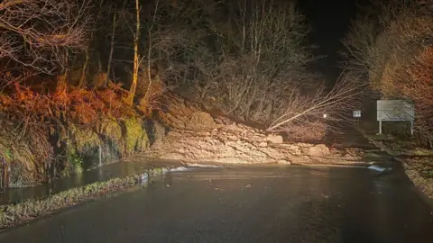 Argyll and Bute council A road blocked by a landslide, with mud and fallen trees covering the road.