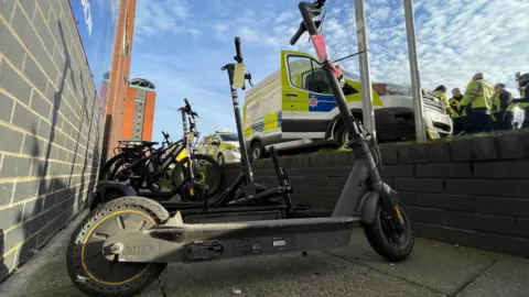 E-bikes and scooters parked near police officers in Derbyshire.