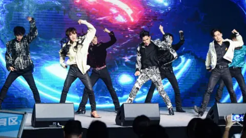 Getty Images The members of K-Pop group WayV punch the air while performing on stage