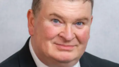 Tynwald Jason Moorhouse, who is wearing a navy suit and has short hair.