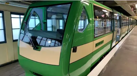 An electric train at the platform. It is green and white.