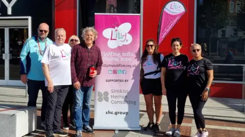 Kevin Day with comedian Alan Davies and a charity banner for the Lily Foundation as well as others wearing the charity logo