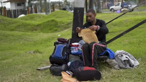 AFP A Venezuelan migrant sorts out donated clothes at an improvised camp near a bus terminal in Bogota on September 11, 2018