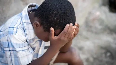 Getty Images A child holding head in hands