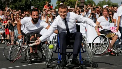 Reuters French President Emmanuel Macron returns the ball while sitting in a wheelchair as he plays tennis on the Pont Alexandre III in Paris, France, on 24 June 2017.