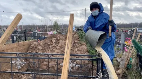 Elizaveta Vereykina/BBC Cemetery worker prepares grave in Vologda