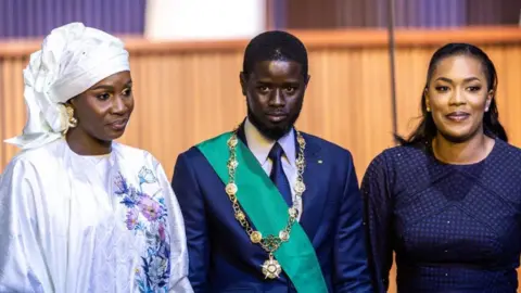 JOHN WESSELS/AFP Bassirou Diomaye Faye (C) and his wives pose after his swearing-in.