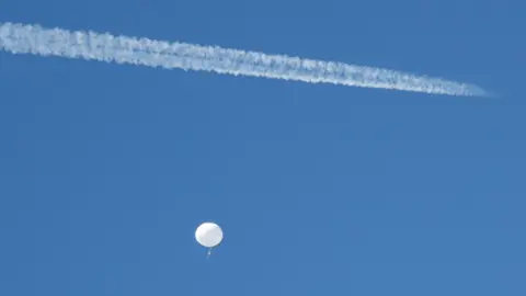 Reuters A jet flies by a suspected Chinese spy balloon as it floats off the coast in Surfside Beach, South Carolina,