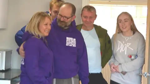 Kevin Cox from Band of Builders shows Cher Little her new kitchen for the first time, also pictured right-left - daughter Georgia, partner Mark, and son Ryan, behind.