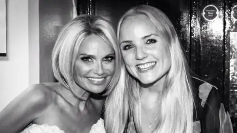 Kerry Ellis A black and white image of Kerry Ellis standing next to Kristin Chenoweth. Kerry has long blonde hair and wears a floral blouse while Kristin has a short blonde bob and wears a strapless white blouse. 