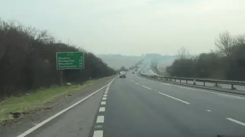 A passenger's point of view, driving onto the A34 from the slip road. The dual carriageway stretches off into the distance among scenic green fields and up a hill.