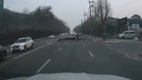 Rep. Yang Bu-nam of Democratic Party's office Screenshot of a video of the sinkhole incident, showing the road caving in and a motorcycle about to fall into the hole, while a car narrowly escapes from falling in.