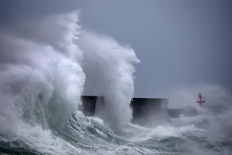 AFP via Getty Images Large waves in western France spraying whitewash up high as it collides with a port 