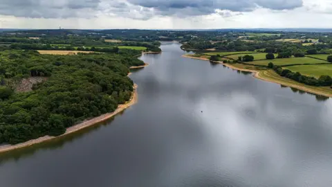 Getty Images An aerial shot of a reservoir, with greenery on the banks and a grey cloudy sky in the distance.