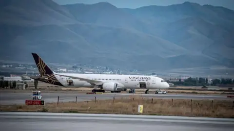 Getty Images یک هواپیمای مسافربری Vistara Airlines در فرودگاه است. کوه ها در پس زمینه دیده می شوند