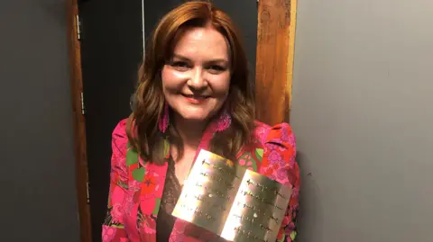 BBC Caryl Lewis holding the Wales book of the year 2023 trophy