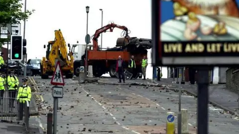 PA Media Debris on an empty road after a riot near a pub where there is sign for it's name "Live And Let Live"