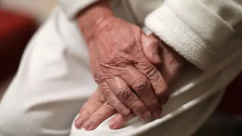 PA Media An image of an elderly woman's hands
