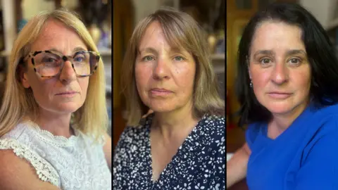 BBC/David Lumb Three women, side by side. The woman on the left has long blond hair, wears tortoise-shell rimmed glasses and a white, sleeveless top. The woman in the middle has brown hair to her shoulders and wears a blue dress with a white floral pattern. The woman on the right has black hair to her shoulders and wears a blue top.