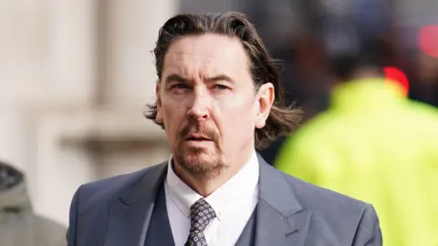 PA Media Richard hall, standing outside the High Court wearing a blue suit and speckled tie
