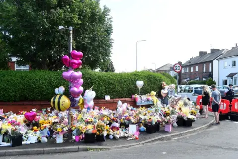 Getty Images Residents look at floral tributes for the victims of a deadly knife attack in Southport